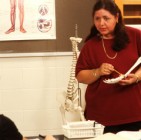 College students and teacher in biology class with skeleton